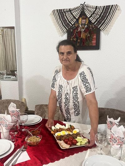 Doamna Elena, presenting a platter of traditional dishes