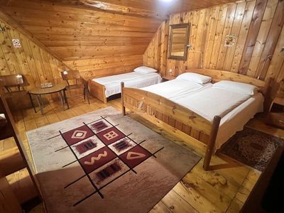 A spacious room, with several beds and traditional rugs