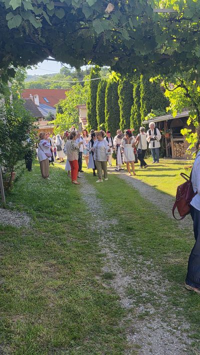 Guests in folk costume, under the courtyard's grapevine arbour