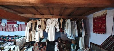 Folk costumes hanging from the wooden beam, in the house-museum