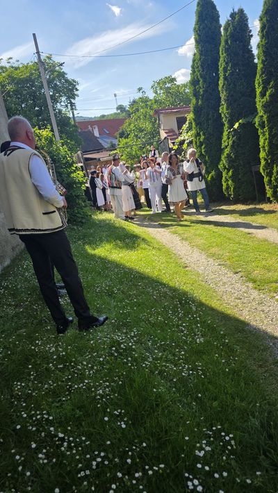 A musician in folk costume, with guests, in the guesthouse courtyard